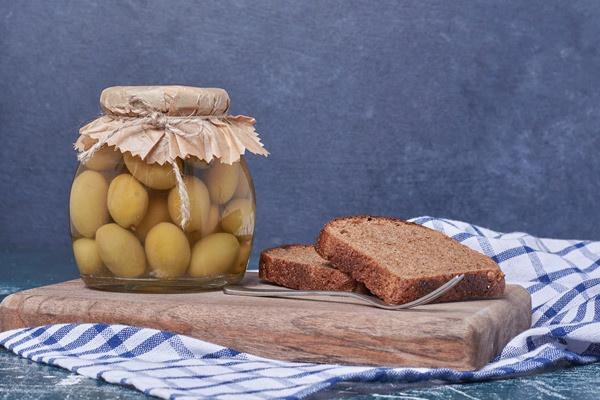 маринованные оливки в стеклянной банке с ломтиками черного хлеба на синем - Оливки и оливки: в чем разница